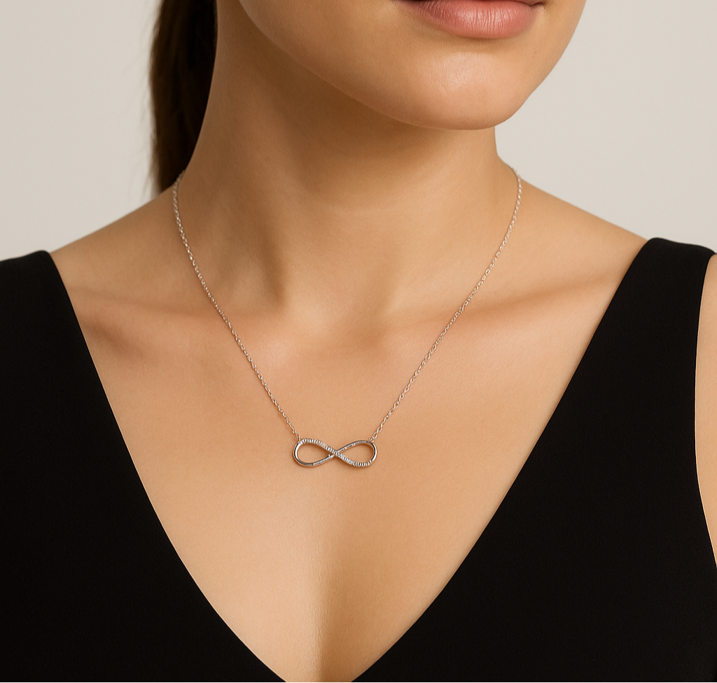Woman wearing a silver infinity necklace against a neutral background